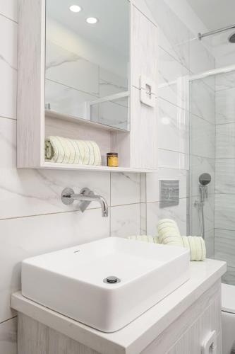 a white bathroom with a sink and a shower at Niki Mountain House in Kamariótis