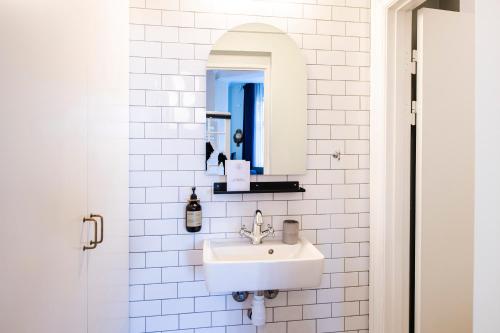 a white bathroom with a sink and a mirror at The Citadel Apartments by Daniel&Jacob's in Copenhagen