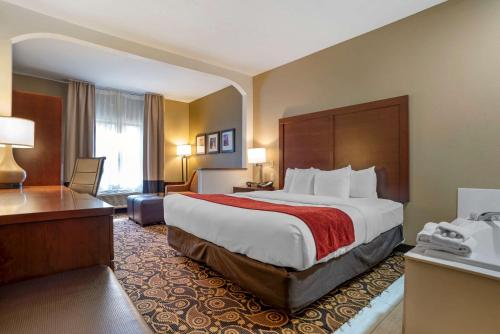ein Hotelzimmer mit einem großen Bett und einem Schreibtisch in der Unterkunft Comfort Suites Mobile East Bay in Daphne