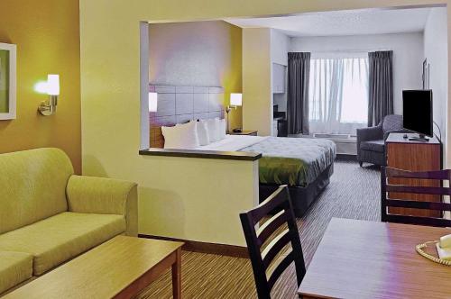 Quality Suites University في الباسو: غرفه فندقيه بسرير واريكه وطاولة