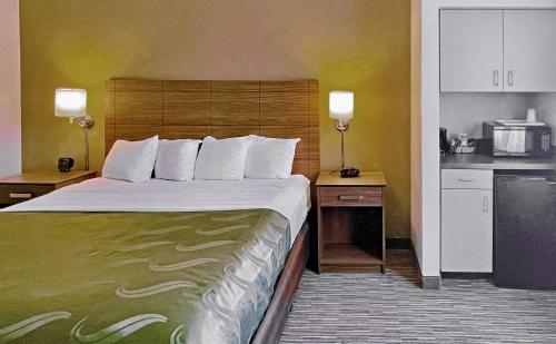 Quality Suites University في الباسو: غرفة فندقية بسرير كبير ومطبخ
