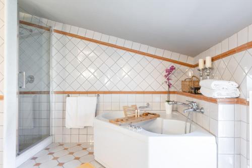 Baño de azulejos blancos con bañera y lavamanos en Fattoria Camigliano, Luxury Farmhouse with Pool inside a Wine Estate, en Capannori