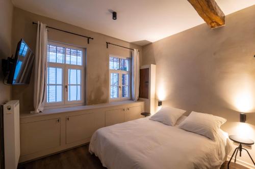 a bedroom with a white bed and two windows at Private en-suite room in the heart of Le Sablon in Brussels
