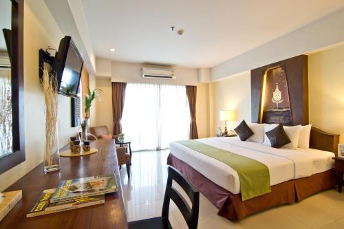 a hotel room with a large bed and a desk at Golden Sea Pattaya - SHA Extra Plus in Pattaya Central