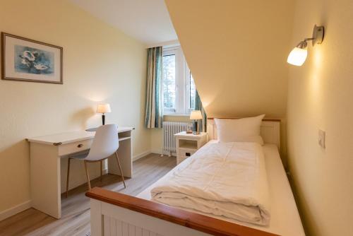 a small room with a bed and a desk at Strandhaus Helene in Wenningstedt