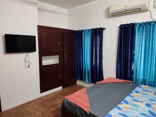 a bedroom with a bed and a flat screen tv at Ritu Homestay in Trivandrum