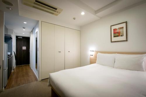 a bedroom with a large white bed and a closet at B:CONTE Asakusa in Tokyo