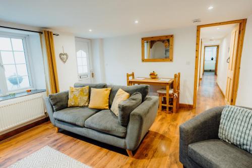 ein Wohnzimmer mit einem Sofa und einem Stuhl in der Unterkunft The Bakehouse - Cosy conversion with Outdoor Sauna in Tenby