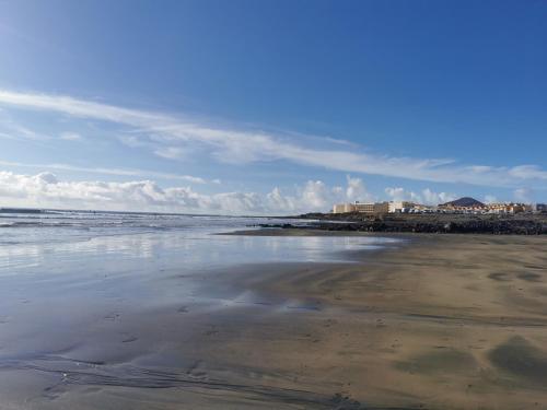 a beach with the ocean and buildings in the background at Modern seafront flat with a private garage in El Médano