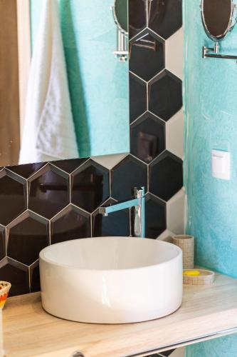 a bathroom with a white sink and black tiles at Ark 68 City Rooms in Rethymno Town