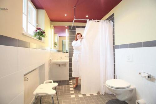 a woman standing in a bathroom with a shower curtain at Hotel Kochsberg in Grebendorf