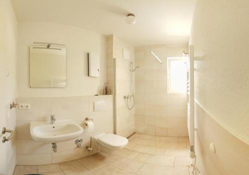 a white bathroom with a sink and a toilet at Möwengruß an der Ostsee in Gelbensande