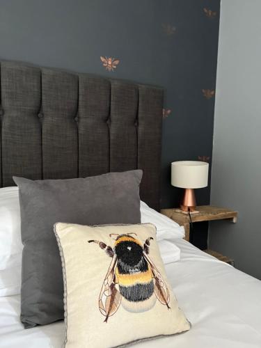 a bed with a pillow with a bee on it at The Bell Inn, Rickinghall in Rickinghall