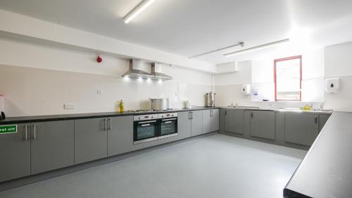 a large kitchen with white cabinets and appliances at Greenhead Hostel in Greenhead