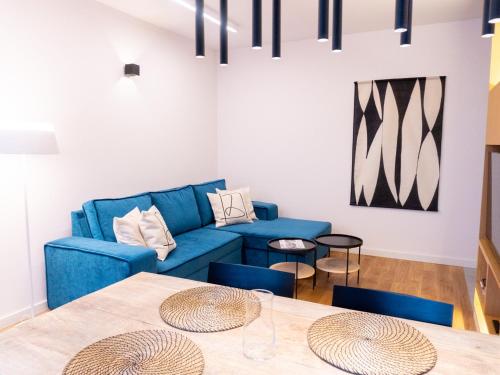 a living room with a blue couch and a table at Hello!Apartments Przy Arkadii in Warsaw