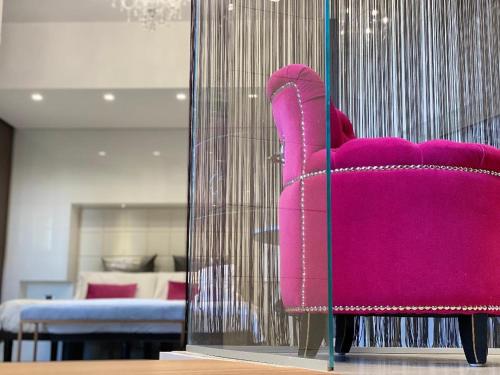 サン・ジョヴァンニ・ロトンドにあるGran Paradiso Hotel Spaのリビングルーム付きの客室で、ピンクの椅子が備わります。