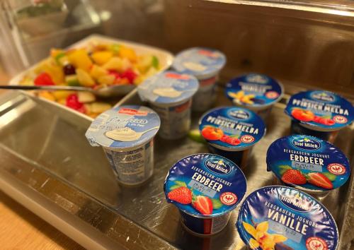 a tray with cups of yogurt and a bowl of fruit at Hotel Löwen in Reit im Winkl