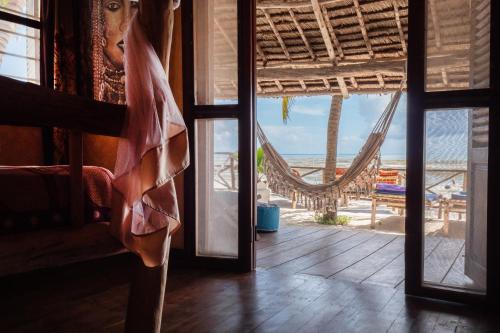 a room with a view of the beach and a hammock at Mamamapambo Boutique Hotel in Jambiani