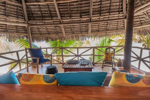 a living room with blue and yellow furniture and a thatched roof at Mamamapambo Boutique Hotel in Jambiani