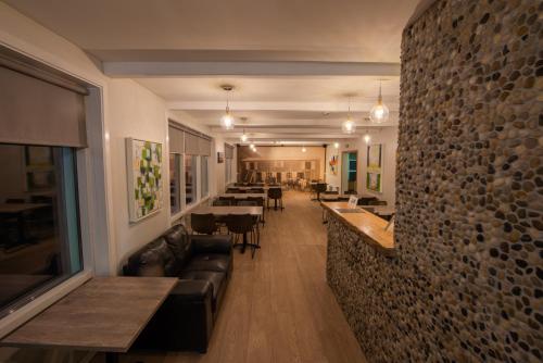 a restaurant with couches and tables and a stone wall at Puffin Hotel Vík in Vík