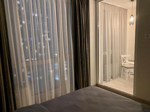 um quarto com uma grande janela com cortinas e uma mesa em New apartments near Slavutych metro station em Kiev