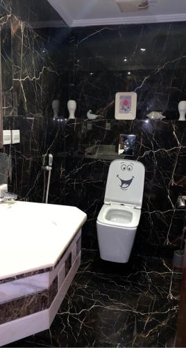 a bathroom with a sink and a toilet with a face drawn on it at شاليه درة العروس in Durat Alarous