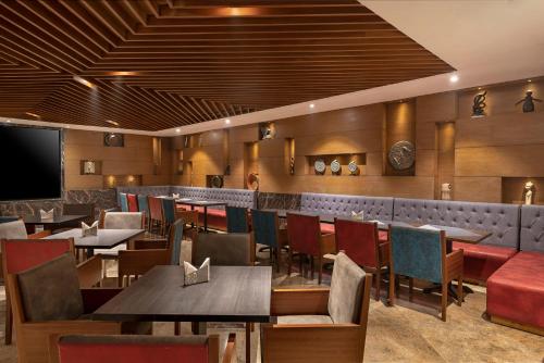 a restaurant with tables and chairs and a bar at Radisson Blu Kaushambi Delhi NCR in Ghaziabad