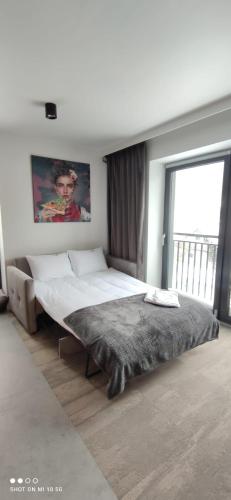 a large bed in a bedroom with a large window at Beskidzka9 & Free Sauna in Szczyrk