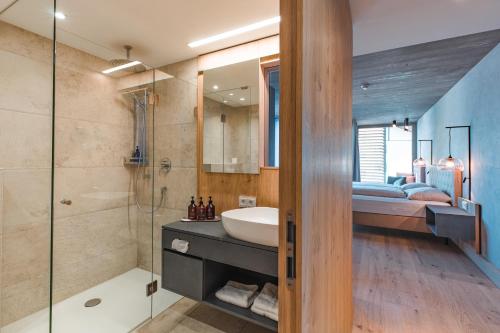 a bathroom with a sink and a shower and a bed at Seehotel Einwaller - adults only in Pertisau