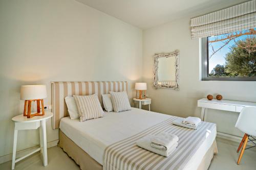 a white bedroom with a bed and a window at Fedra Guest House in Plakias