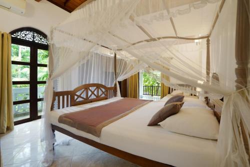 a bedroom with a bed with a canopy at The Villa Blue Sky in Unawatuna