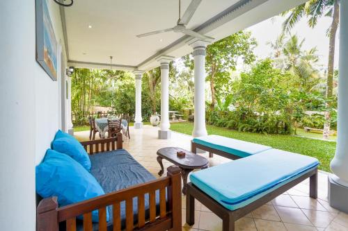a screened in porch with a couch and tables at The Villa Blue Sky in Unawatuna