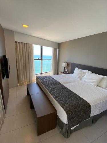 a bedroom with a large bed and a large window at Beach Class Internacional apartamento in Recife