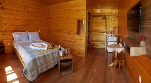 ein Schlafzimmer mit einem Bett in einer Holzhütte in der Unterkunft Amanhecer na Serra in Urubici