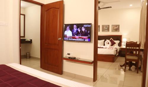 a living room with a television and a bed at Bhasuri Inn Guruvayoor in Guruvāyūr