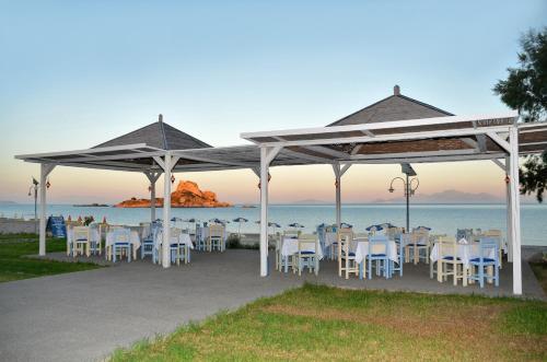 a group of tables and chairs under a pavilion near the ocean at Kordistos Hotel in Kefalos