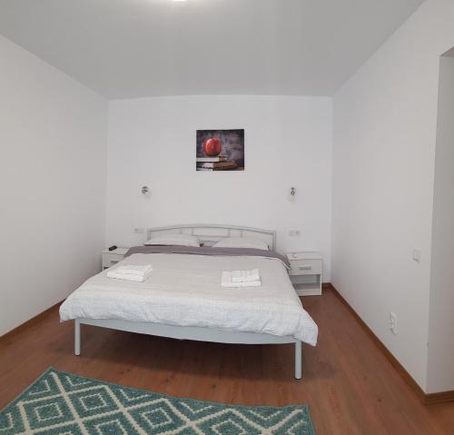 a bedroom with a white bed with a green rug at Apartament 10 Budiu in Târgu-Mureş