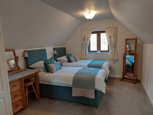1 dormitorio con 2 camas, mesa y espejo en Innisfree Cottage, en Eyam