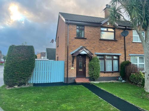 a brown brick house with a blue fence at Home from Home in Six Road Ends