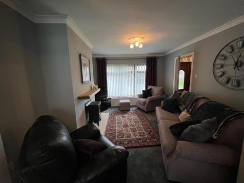a living room with couches and a clock on the wall at Home from Home in Six Road Ends