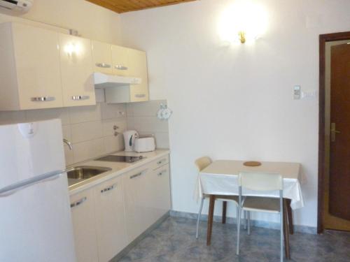 małą kuchnię ze stołem i białą lodówką w obiekcie Apartments Spada w Poreču