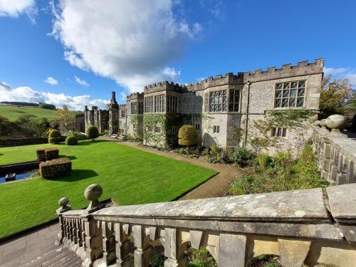an old castle with a green lawn and a balcony at Innisfree Cottage in Eyam