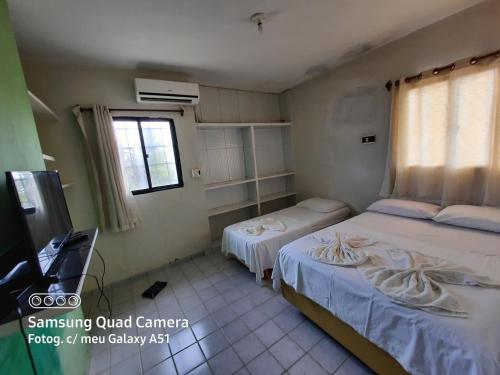 mały pokój z 2 łóżkami i telewizorem w obiekcie Prainha Apart-Hotel w mieście Baía da Traição