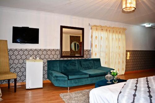 a living room with a green couch and a tv at MaU Bed and Breakfast in Krugersdorp