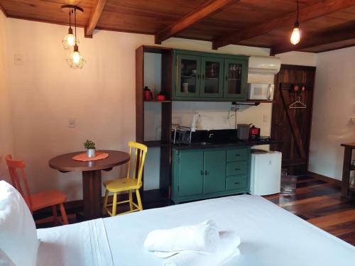 a kitchen with green cabinets and a table and a bed at Caminhos da Serra do Tabuleiro - Chalé do Lago in São Bonifácio