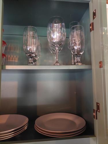 four wine glasses and plates on a shelf at Caminhos da Serra do Tabuleiro - Chalé do Lago in São Bonifácio