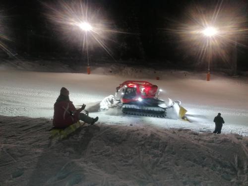 a person sitting in the snow next to a snowmobile at Chata - Dom Horskej služby Jasna in Demanovska Dolina
