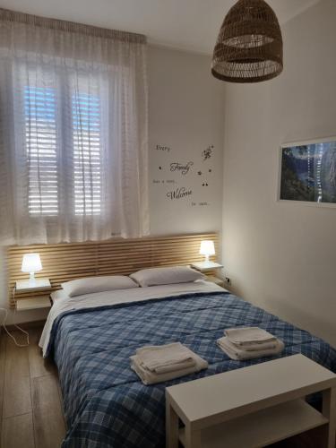 um quarto com uma cama com um cobertor azul e uma janela em FRAiMARI Home em Trapani