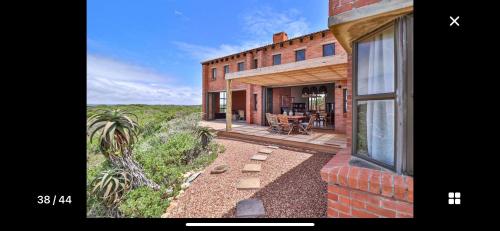 a brick house with a patio and a window at 4 Zwaan in Jeffreys Bay