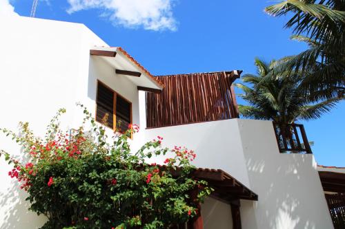a white building with a flowering bush next to a palm tree at Casa Colibrí Tankah in Tulum